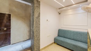 Une pièce avec une porte sombre, un mur d’accent en pierre, un canapé bleu clair et un éclairage encastré au plafond.