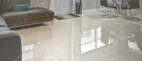 Un vaste espace de vie doté d’une grande fenêtre, d’un ventilateur de plafond et d’une table à manger avec des chaises.