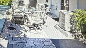 An outdoor patio with a dining table and chairs, a large umbrella, and a stone-tiled floor. - Modern Spacious Beach Villa 1 Pompano Beach (Pompano Beach)