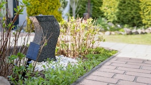 A garden pathway with a unique stone sculpture, surrounded by greenery and a brick path.