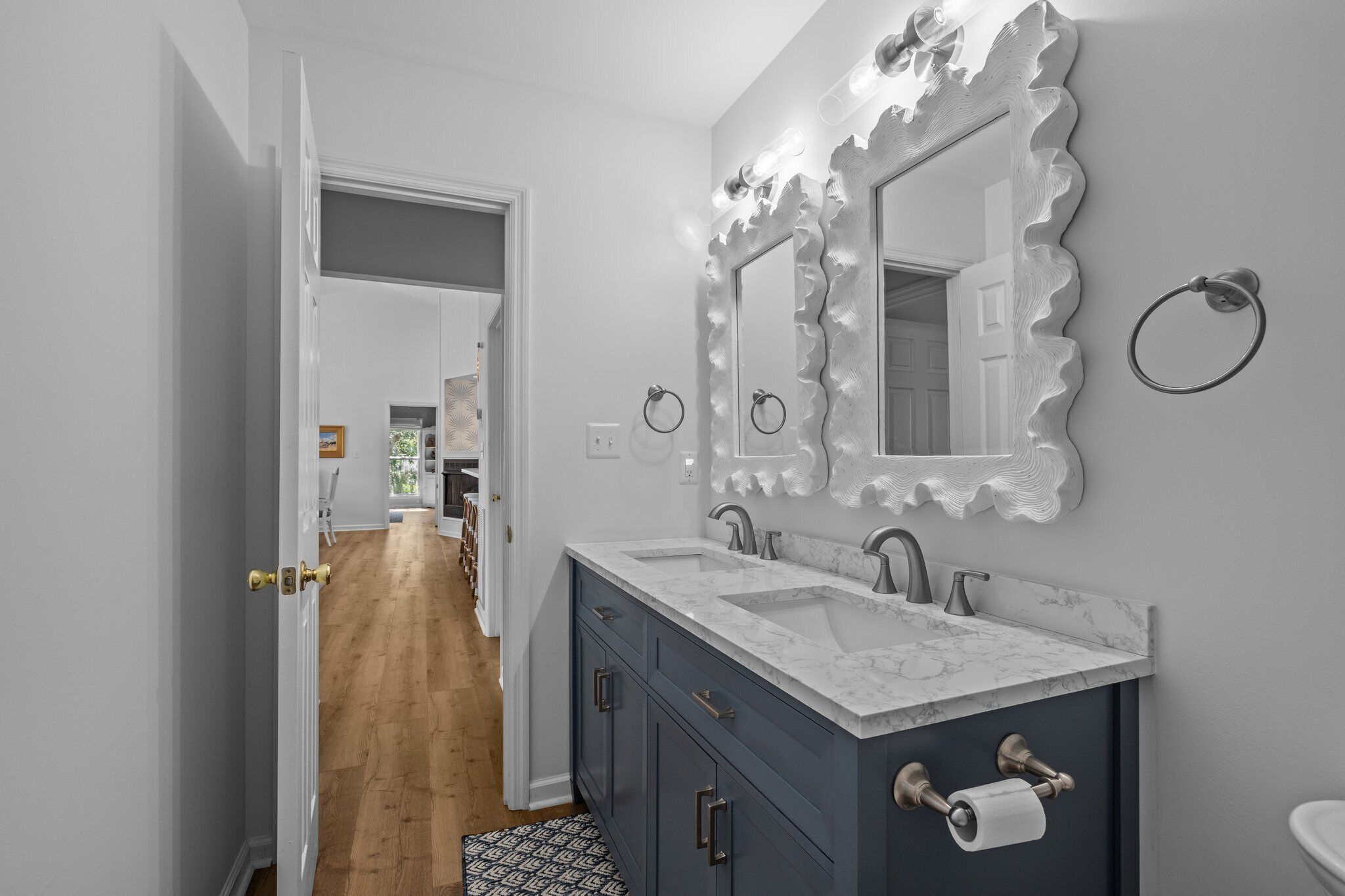 A modern bathroom with a vanity, two sinks, and a large mirror with lights.