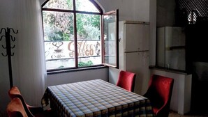A small room with a table and two red chairs, a window with a view of trees, and a sign reading "Coffee". - Akasya Pansiyon & Apart (Anamur)