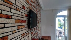 A room with a brick wall and a mounted television. - Akasya Pansiyon & Apart (Anamur)
