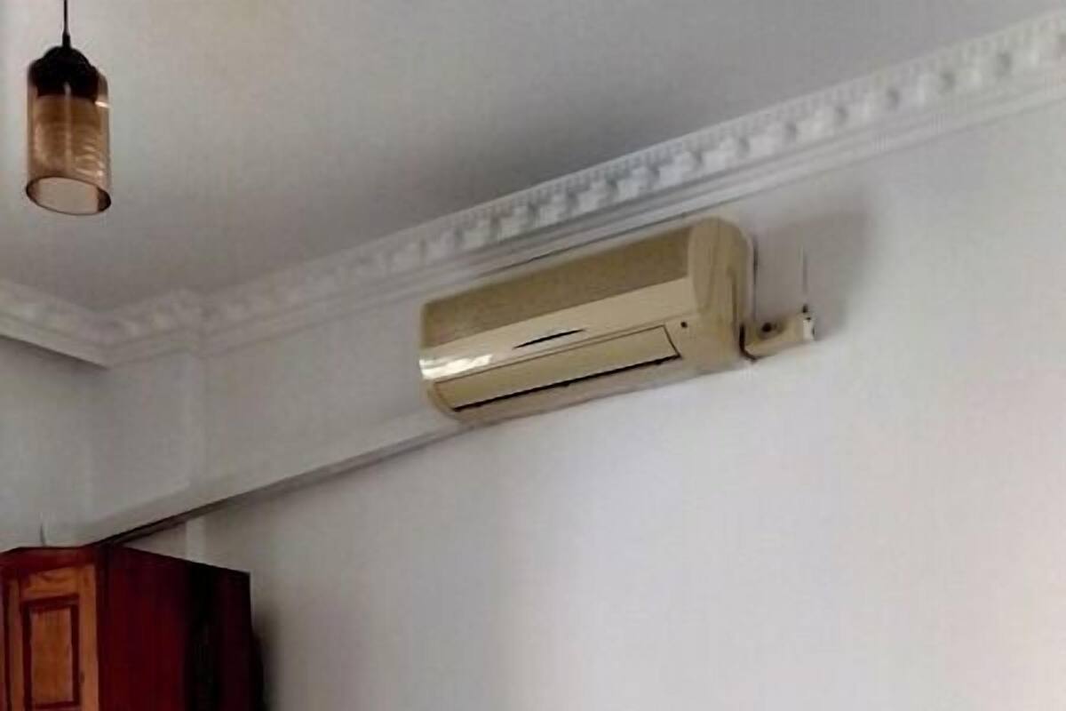 Ein Hotelzimmer mit zwei Betten, einem Holzschrank und einer Klimaanlage an der Wand.