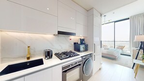 A modern kitchen with a gas stove, a coffee maker, and a washing machine.