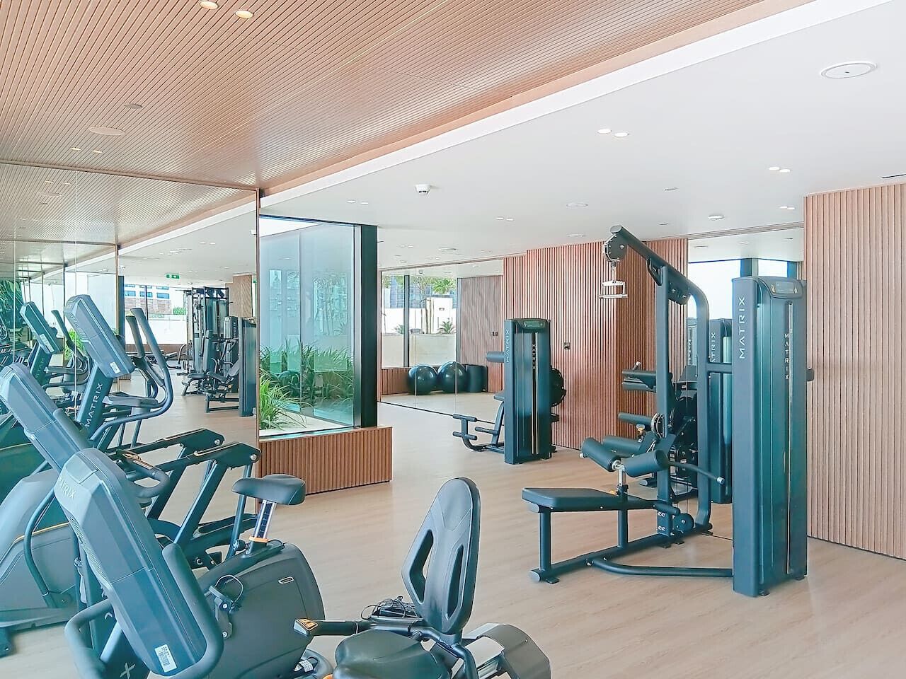 Ein modernes Fitnessstudio mit unterschiedlichen Trainingsgeräten, darunter Laufbänder und Kraftgeräte, sowie einer großen Spiegelwand.