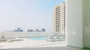 A rooftop terrace with a pool, lounge chairs, and a view of the city skyline.