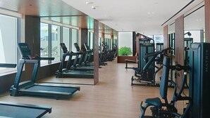 A modern gym with treadmills, elliptical machines, and weight equipment.