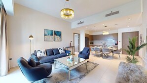 A modern living room with a sofa, armchairs, and a coffee table. There is a dining area with a table and chairs. The kitchen is visible in the background. - Vibrant 2 Bedroom l Pool with Burj Khalifa View (Downtown Dubai)
