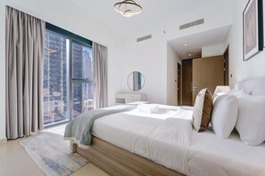 A modern hotel bedroom with a large bed, a view of the city, and a walk-in closet. - Vibrant 2 Bedroom l Pool with Burj Khalifa View (Downtown Dubai)