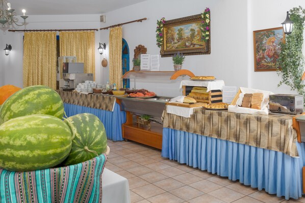 Una habitación con una mesa de buffet, una máquina de café y una sandía grande sobre una mesa.