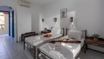 A hotel room with two beds, a small table, a nightstand, and a potted plant.