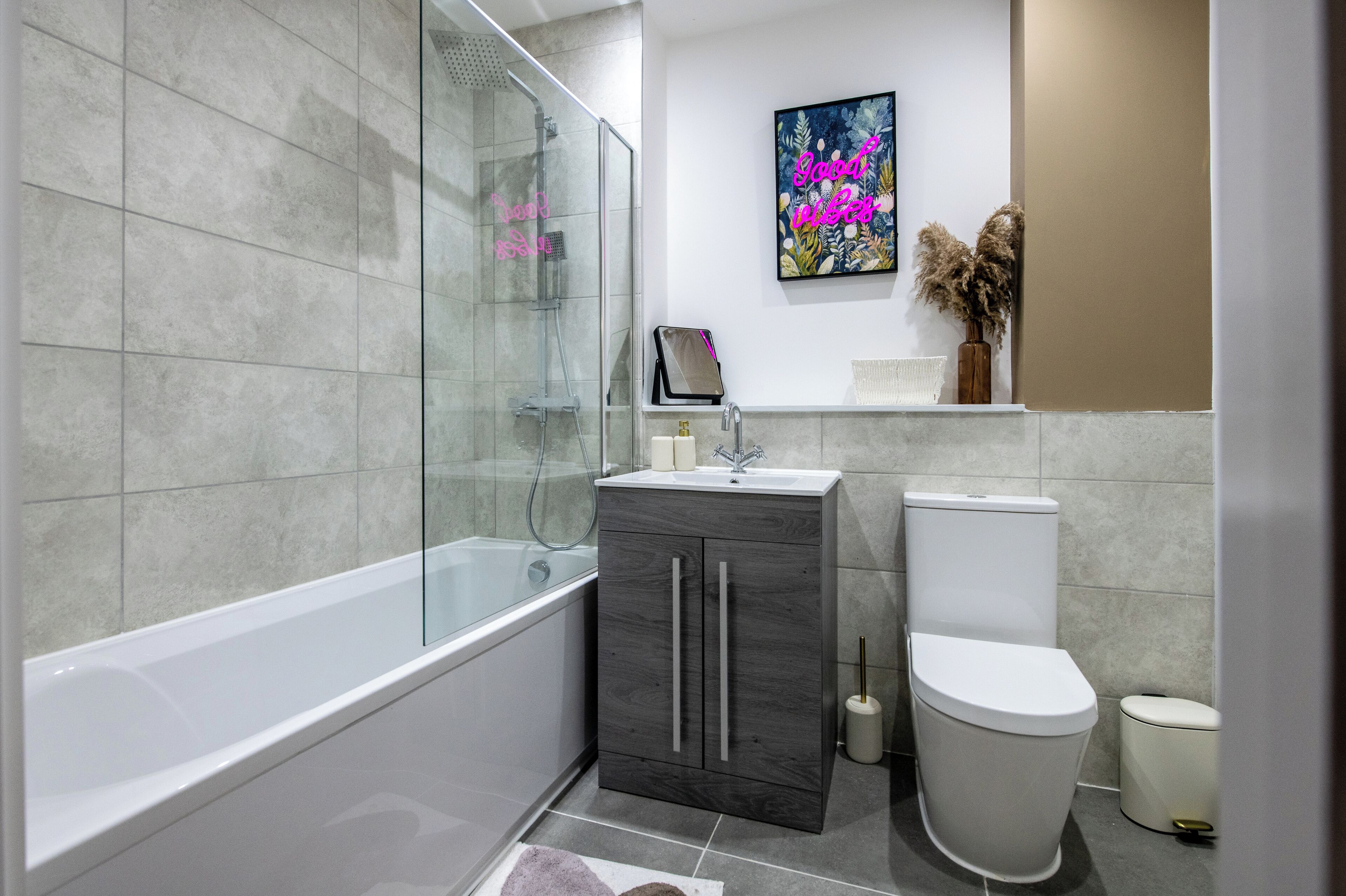 Une salle de bain moderne avec une douche à parois de verre, un lavabo blanc, des toilettes et un meuble de rangement.