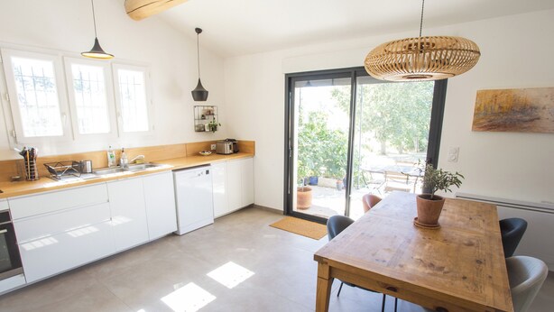 Una cucina moderna con mobili bianchi, un piano di lavoro in legno e un tavolo da pranzo con sedie.