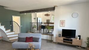 Un soggiorno moderno con un divano grigio, un tavolino in legno e una TV a schermo piatto su un supporto in legno.
