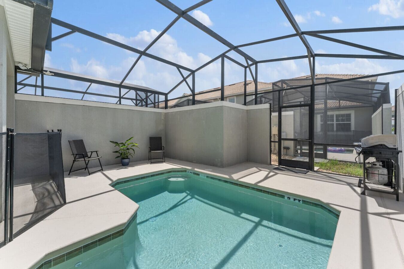 A swimming pool with a glass enclosure, a chair, a potted plant, and a grill area.