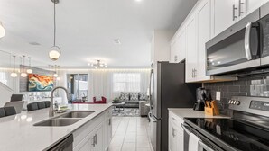 Una cocina moderna con electrodomésticos de acero inoxidable, una isla grande con un lavamanos y un comedor con un sofá rojo.