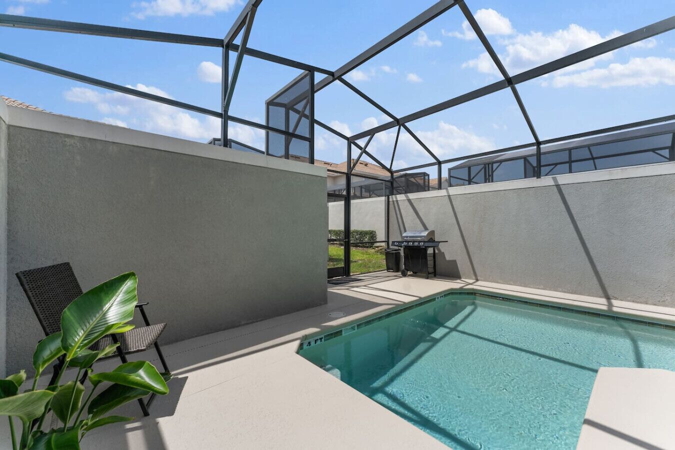 A modern outdoor pool area with a glass enclosure, a grill, and a chair.