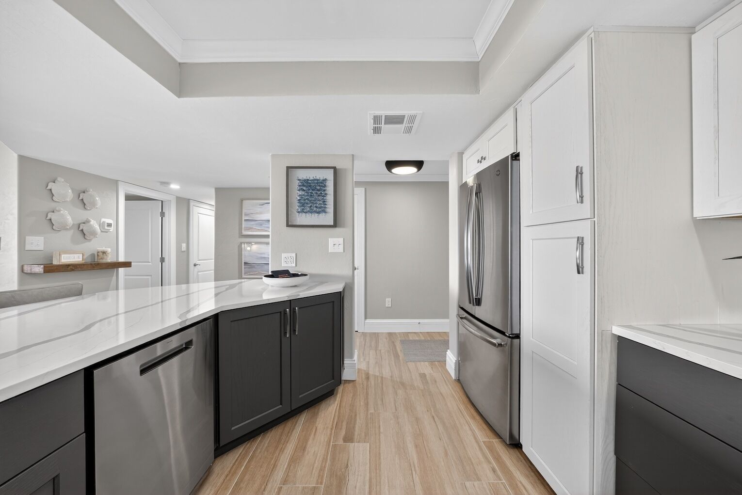 A modern kitchen with dark cabinets, stainless steel appliances, and a marble countertop.