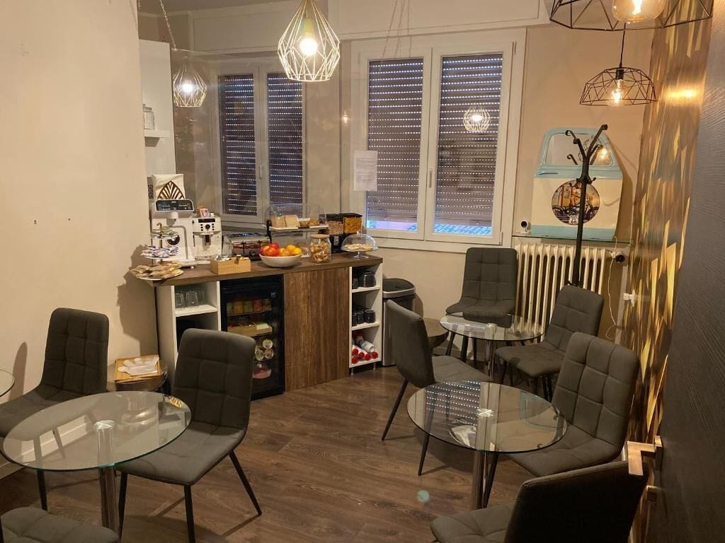 A modern kitchen with a dining area, featuring a coffee machine, fruit bowl, and various kitchen items.