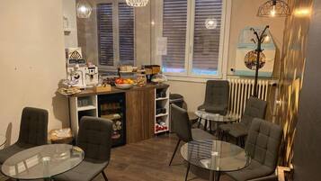 A modern kitchen with a dining area, featuring a coffee machine, fruit bowl, and various kitchen items.