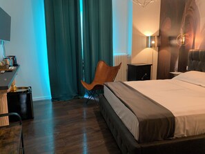 A hotel room with a bed, a chair, a desk with a lamp, and a radiator. - Suite Lame 37 Rental Rooms (Bologna)