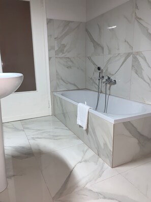 A modern bathroom with a marble floor, a white bathtub, and a sink. - Suite Lame 37 Rental Rooms (Bologna)