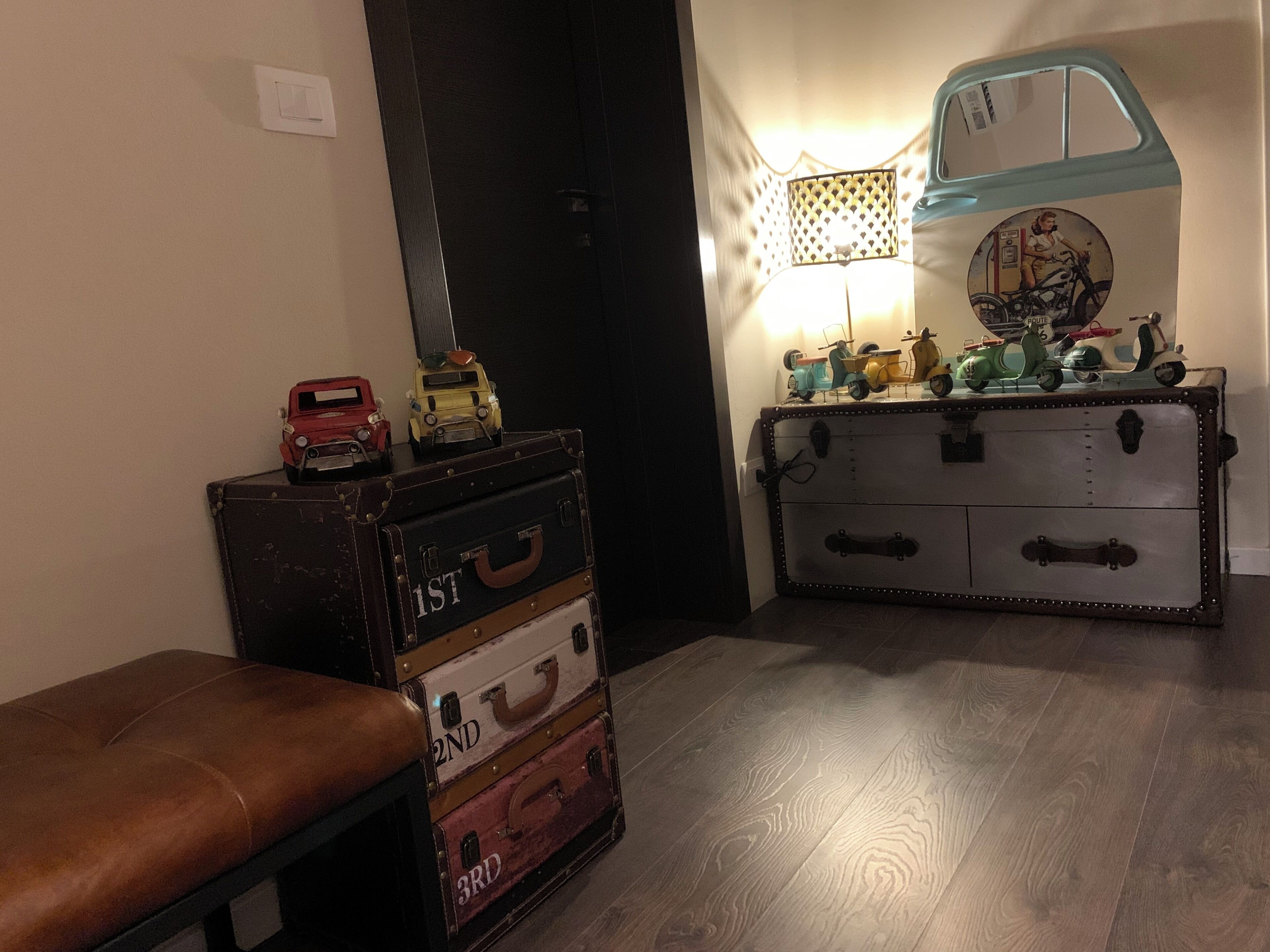 Een kamer met een bankje, oude koffers, een lamp en een wandplank met speelgoed.