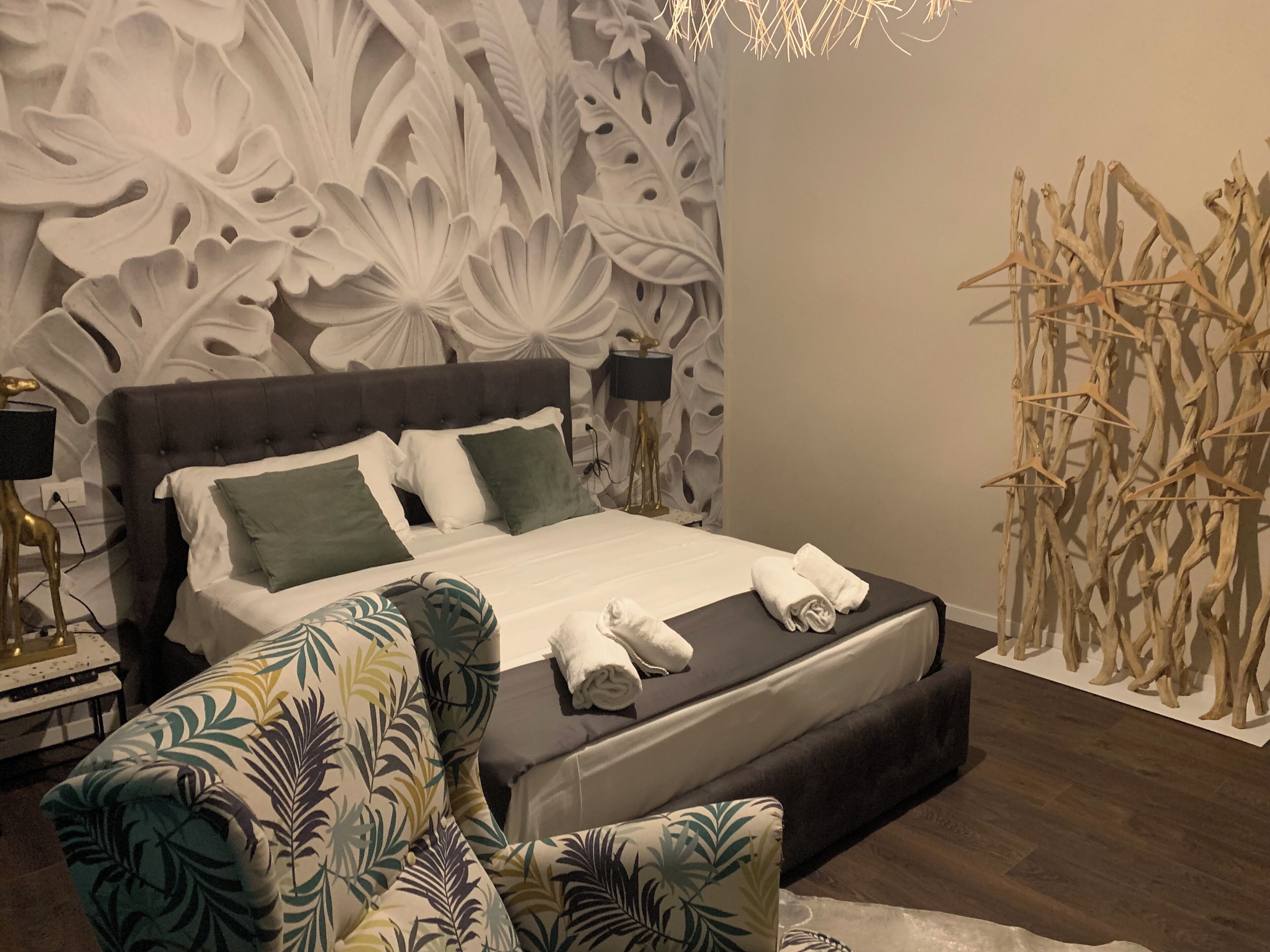 A bedroom with a large bed, a nightstand, a lamp, and a wall with a decorative pattern.