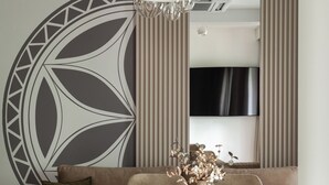 A modern dining area with a round table, cushioned chairs, a decorative wall piece, and a mounted TV. - Apartament przy Potoku 25 z parkingiem (Zakopane)