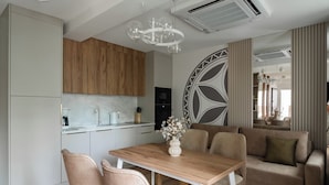 A modern kitchen with wooden cabinets, a marble countertop, and a dining area with a wooden table and chairs. - Apartament przy Potoku 25 z parkingiem (Zakopane)