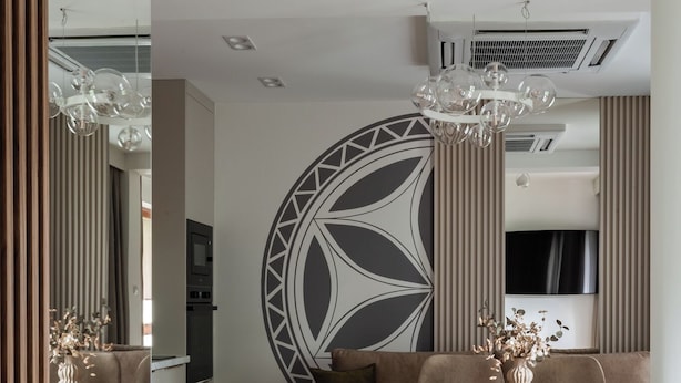 A modern dining area with a round table, chairs, and a decorative wall piece. - Apartament przy Potoku 25 z parkingiem (Zakopane)