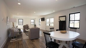 A spacious living area with a round dining table, multiple seating options, and large windows providing natural light. - Modern Farmhouse Getaway (Leesburg)