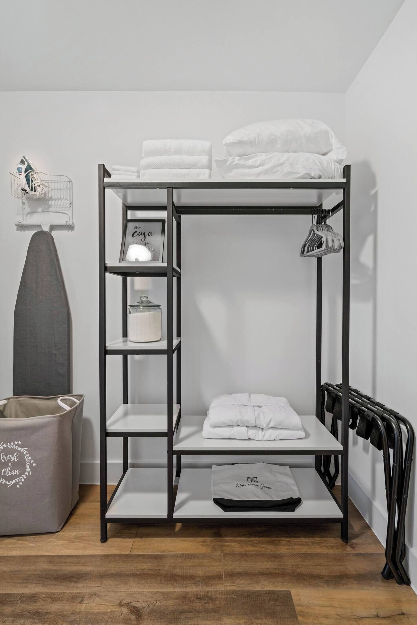 Een stapelbed met witte beddengoed, een klein plankje met een kaars en een ingelijste foto, en een radiator aan de rechterkant.