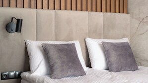 A modern bedroom with a tufted headboard, two bedside lamps, and a bed with white and gray bedding. - Apartament MONTE z jacuzzi i sauną (Zakopane)