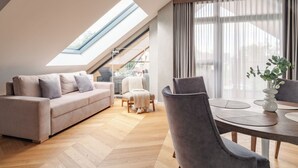 A modern living room with a high ceiling, a sofa, a dining table, and a chair. - Apartament MONTE z jacuzzi i sauną (Zakopane)