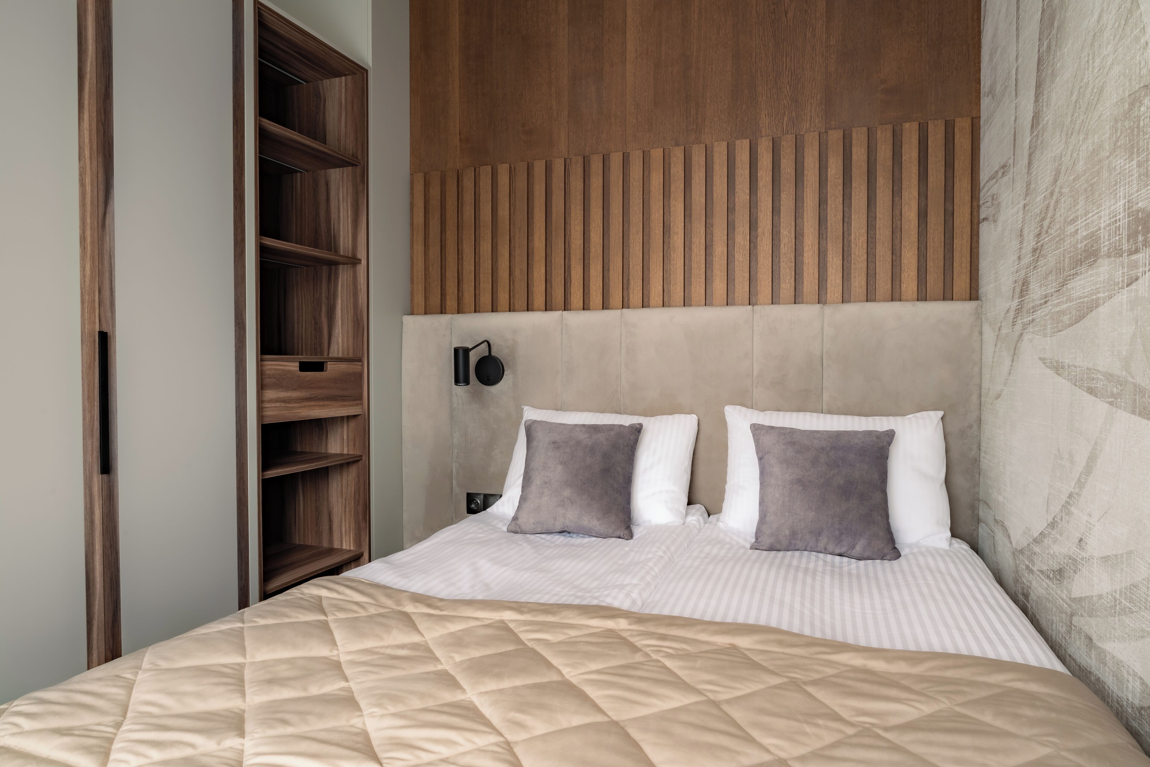 A bedroom with a bed, a wooden headboard, and a nightstand with a lamp.