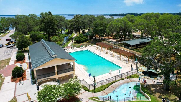 Ein Hotel mit großem Schwimmbad, Sitzgelegenheiten im Freien und Blick auf das Wasser.