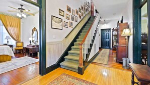 Ein geräumiges Wohnzimmer mit Holzböden, einer Treppe und einem großen Fenster mit Vorhängen.