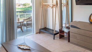 Habitación de hotel con balcón, una mesa de madera, sofá, televisión y armario.
