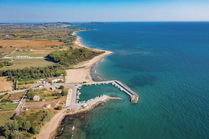 An aerial view of a coastal area with a marina, sandy beach, and surrounding fields. - Sun Sea Escape Kourouta Beachside Getaway (Ilida)