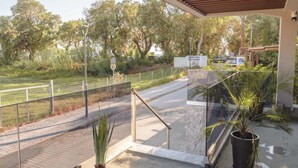 A balcony with a view of a road, a fence, and greenery. - Seaside Nest in Kourouta Steps From the Beach (Ilida)