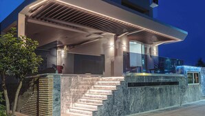 A modern building with a glass facade, a set of stairs leading to a covered entrance, and a well-lit outdoor area. - Seaside Nest in Kourouta Steps From the Beach (Ilida)