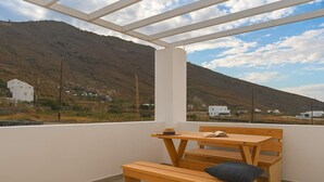 A balcony with wooden furniture and a view of a mountainous landscape.