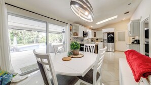A modern kitchen with white cabinetry, a dining table with chairs, and a red towel on a bench. - Fishing Dock & Canal Views: Fort Lauderdale Home! (Fort Lauderdale)