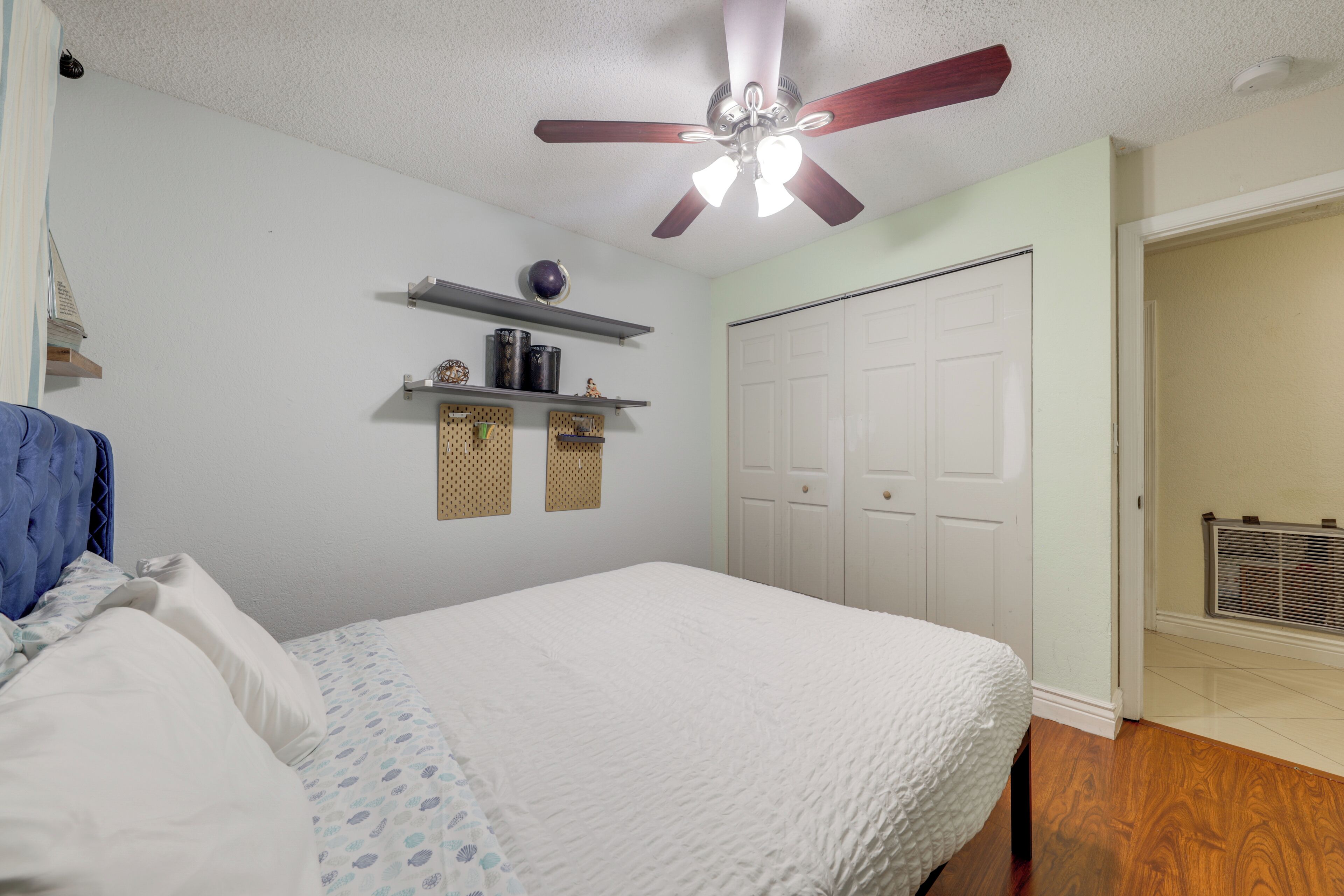 A bedroom with a bed, a ceiling fan, a wardrobe, and a radiator.