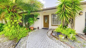 A house with a paved entrance, surrounded by various plants and a small garden area. - Fishing Dock & Canal Views: Fort Lauderdale Home! (Fort Lauderdale)