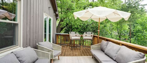 A covered outdoor seating area with wicker furniture and a large umbrella.