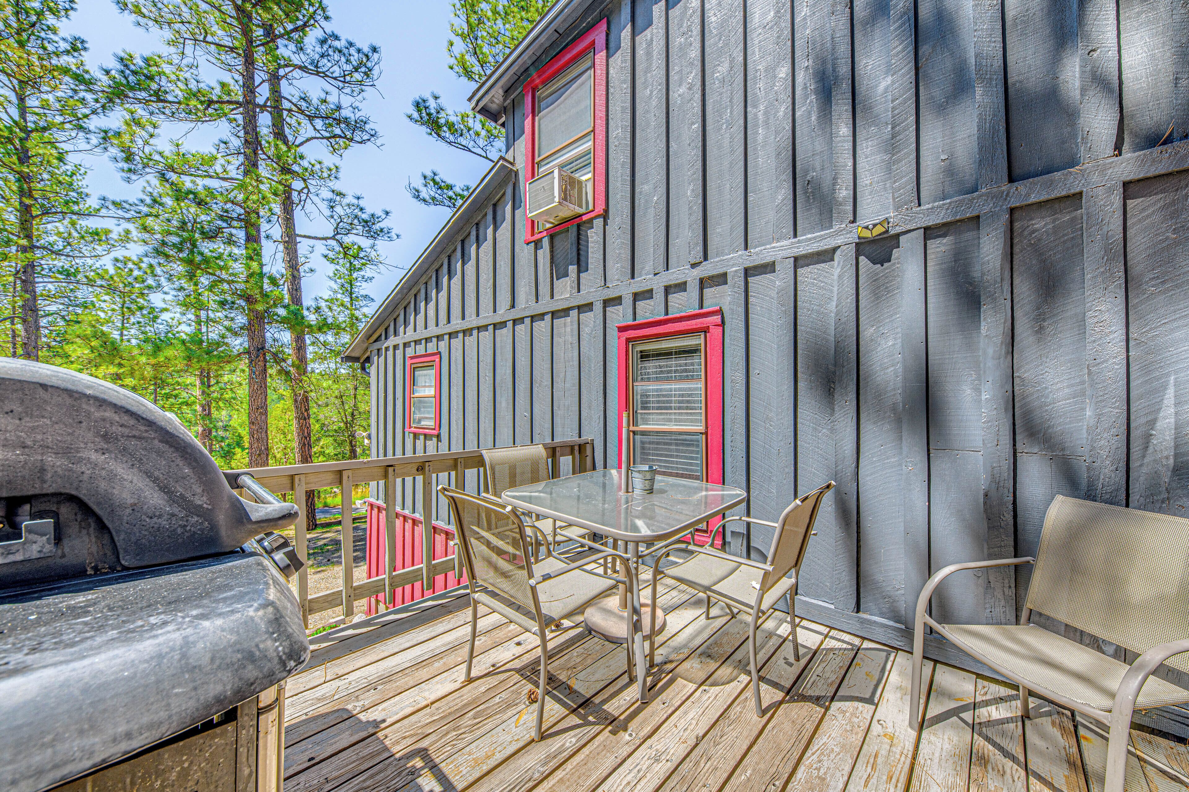 A wooden deck with a grill, a table, and chairs.