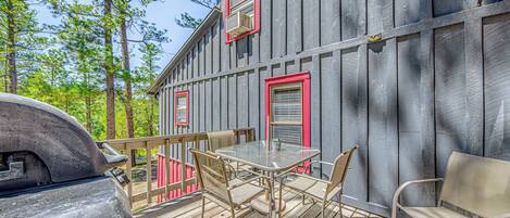 A wooden deck with a grill, a table, and chairs.